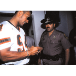 the rock 2000 comic images rock solid 016 Man in football jersey signs autograph for police officer inside building.